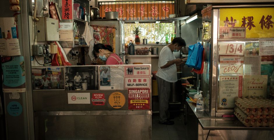 Staff preparing food at a busy hawker stall — gel baiting lets stalls keep trading through treatment