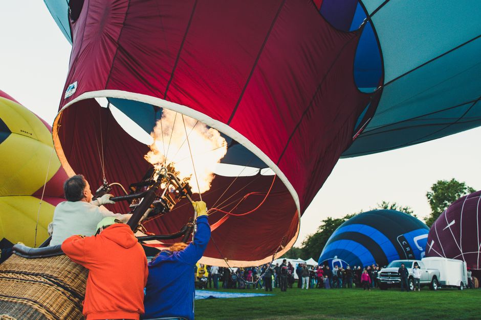 Dynamic scene of adults managing a hot air balloon at an outdoor festival.