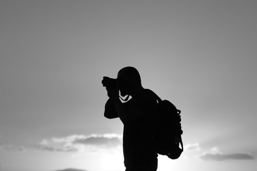 Free Black and white silhouette of a photographer capturing the sunset in Alghero, Sardinia. Stock Photo