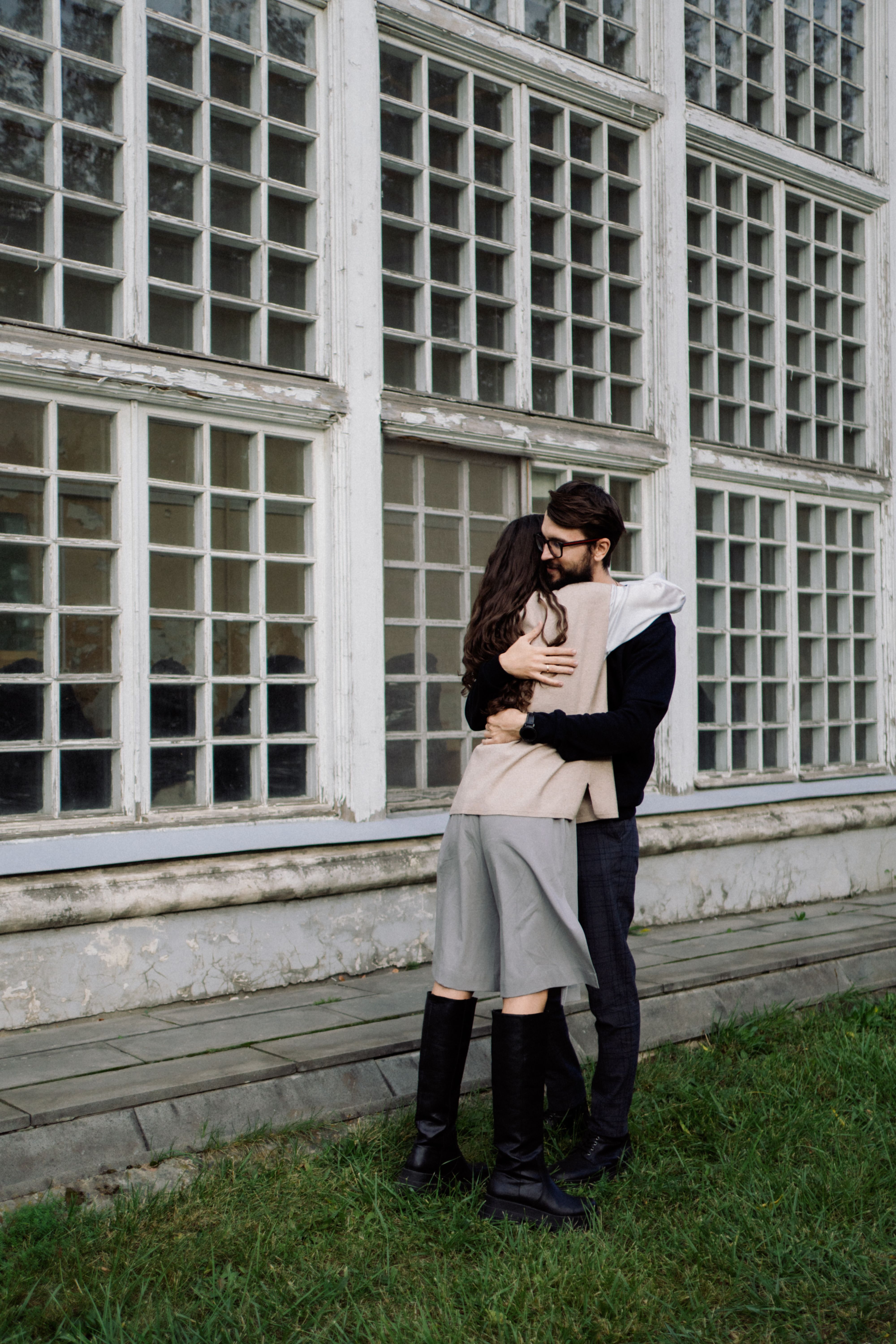Couple Hugging near Building Windows · Free Stock Photo