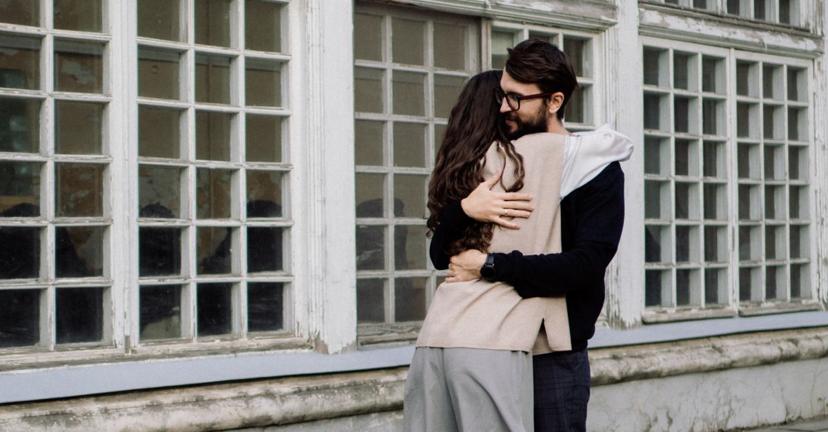 Couple Hugging near Building Windows · Free Stock Photo