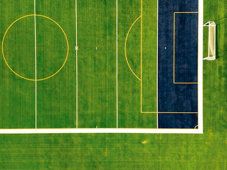 Drone shot capturing a vibrant green soccer field with goal post.