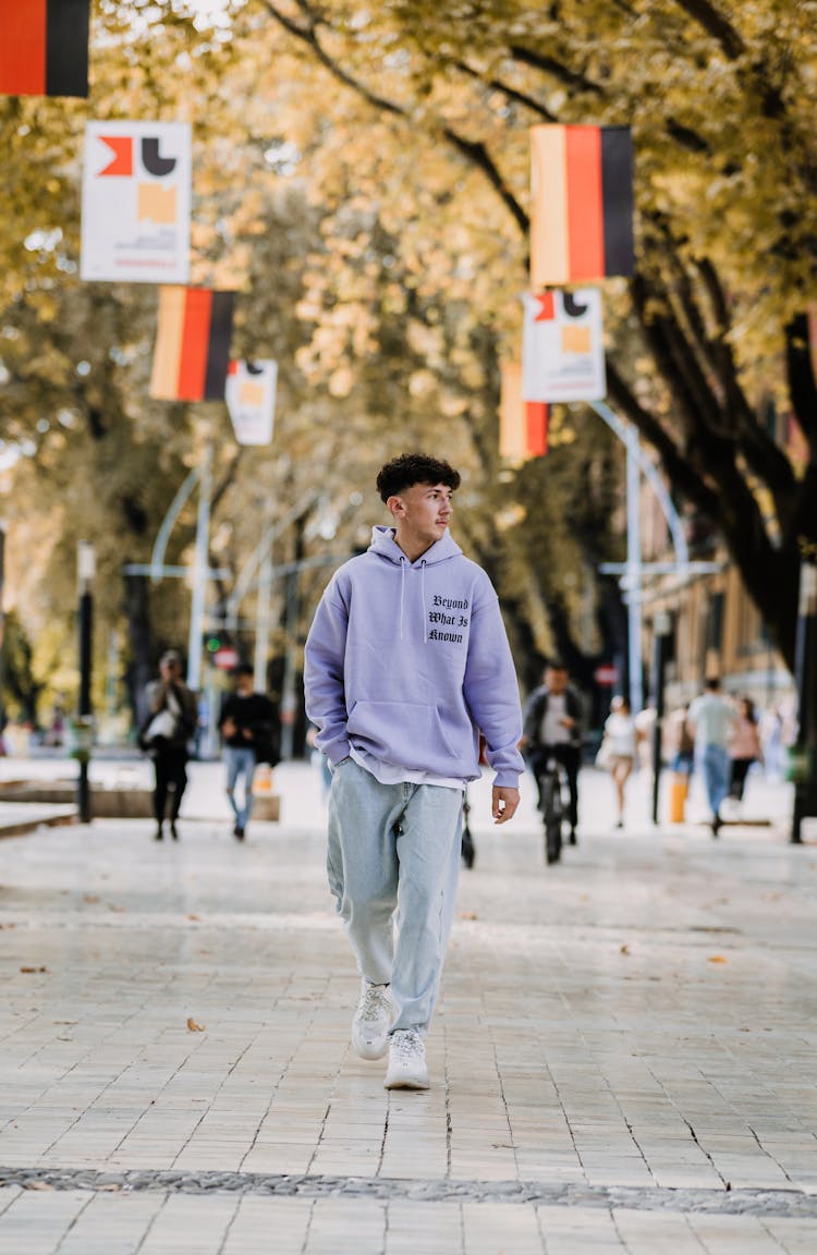 Young Man In Hoodie Walking Down Street