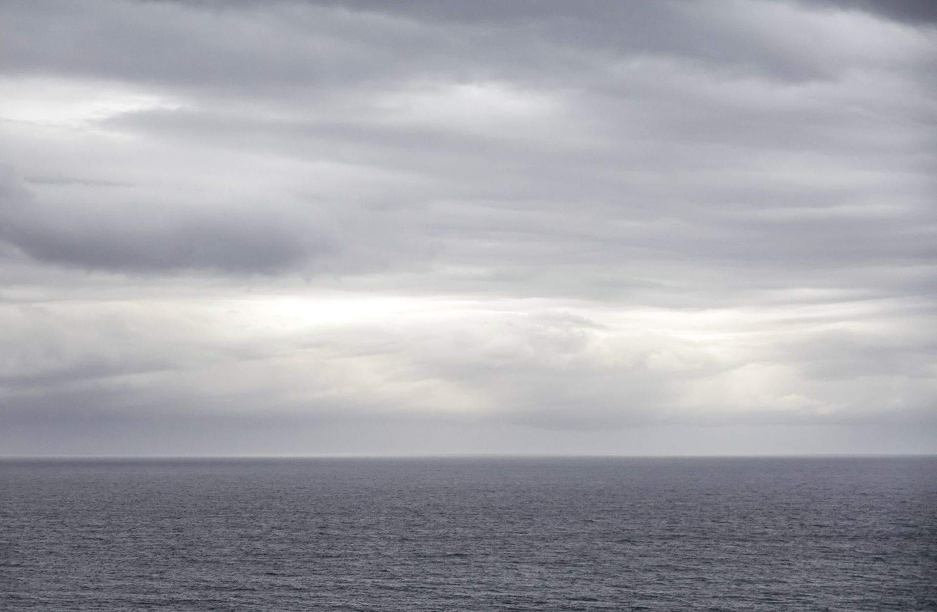 Grey navy frigate at sea under overcast skies