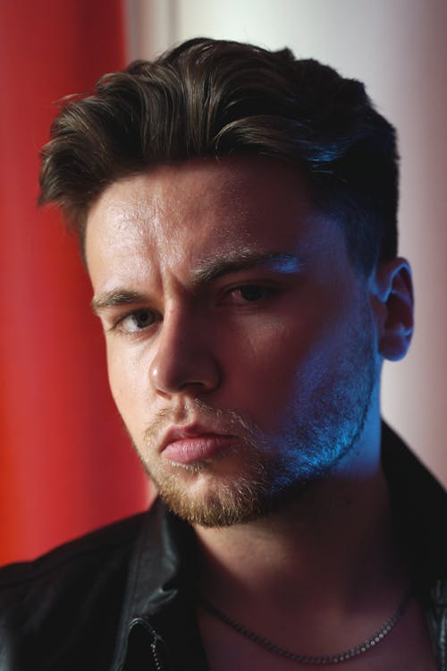 Free Close-up portrait of a handsome man with a beard in moody lighting. Stock Photo