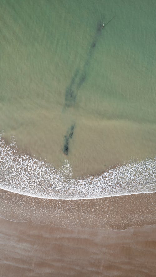 Aerial View of Wave Hitting Sandy Beach