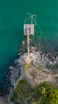 Stunning aerial shot of a pier overlooking the rocky coast of Pornic, France with vibrant turquoise waters.