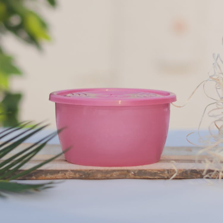 A Pink Plastic Container on a Wooden Board