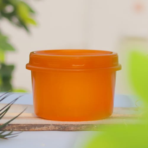 An Orange Plastic Container on a Wooden Board