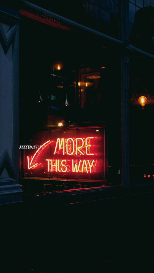 Free Vibrant red neon sign directing the way at night in an urban setting with reflections. Stock Photo