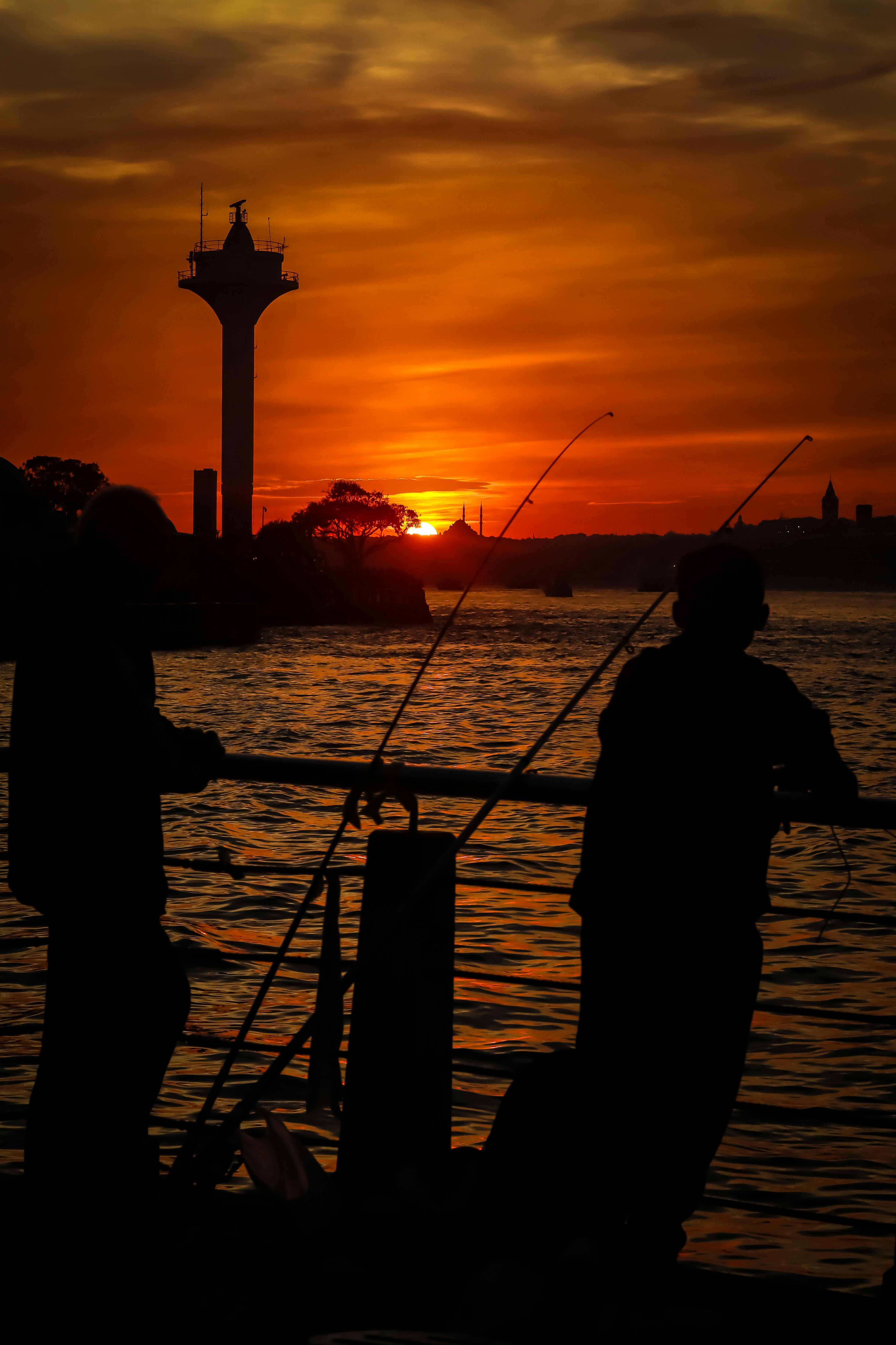 Silhouetted Fishermen Fishing on a Pier at Sunset · Free Stock Photo