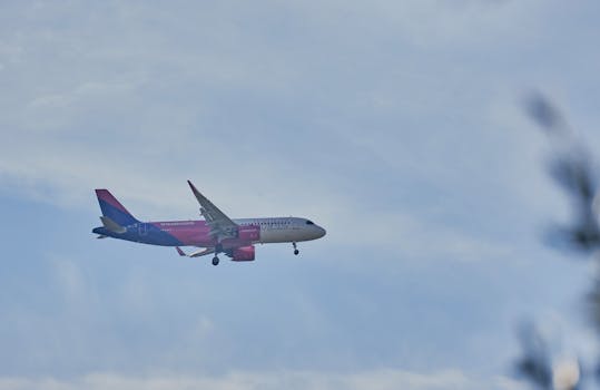 Wizz Air aircraft descending through a cloudy sky at Rinas Airport, Albania.