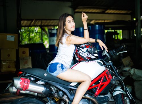 Free An adult woman sitting on a motorcycle indoors, looking confident and stylish. Stock Photo