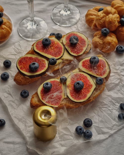 Fresh Figs Served with Blueberries and Pastries next to Snuffed Candle