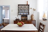 A charming dining room featuring wooden furniture, vintage decor, and a fresh fruit bowl on a sunny day.