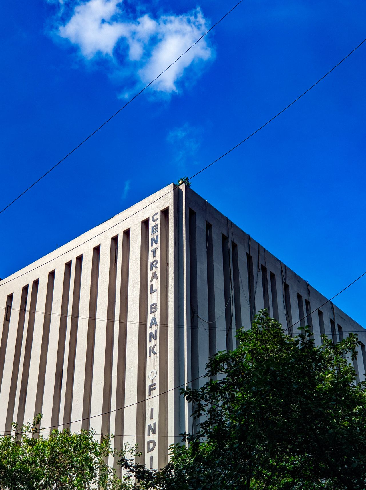 Geometric architecture of Central Bank of India against a bright blue sky.