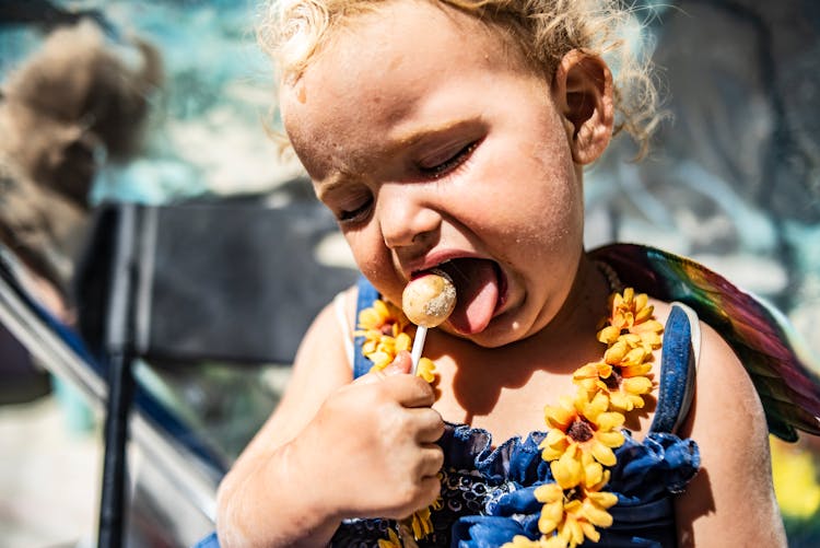 Photograph Of A Kid Eating A Lollipop