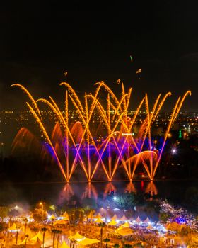 Colorful fireworks illuminate the night sky over a vibrant city festival.