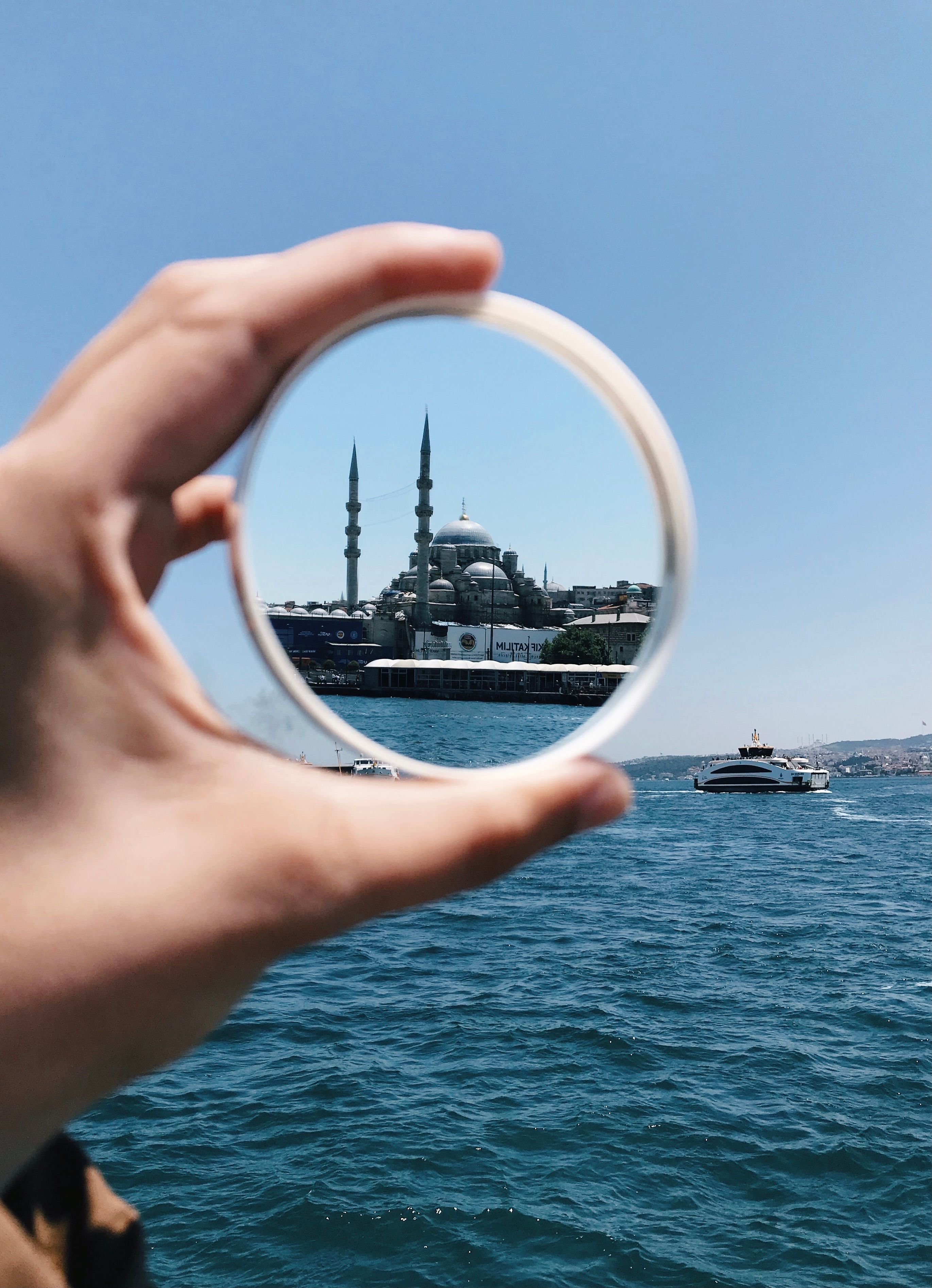 A unique view of Istanbul's New Mosque captured through a hand-held mirror reflecting over the Bosphorus.