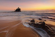 日出时分，海浪拍打着岩石，宁静的海滩场景捕捉到了大自然的美丽