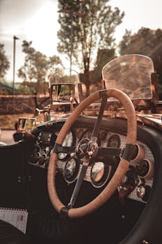 Close-up of a classic vintage car interior showcasing a wooden steering wheel and retro dashboard.