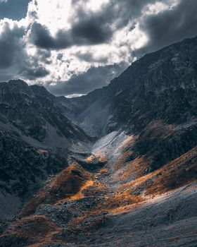 Stunning twilight view of a mountain valley with dramatic clouds and vibrant colors.