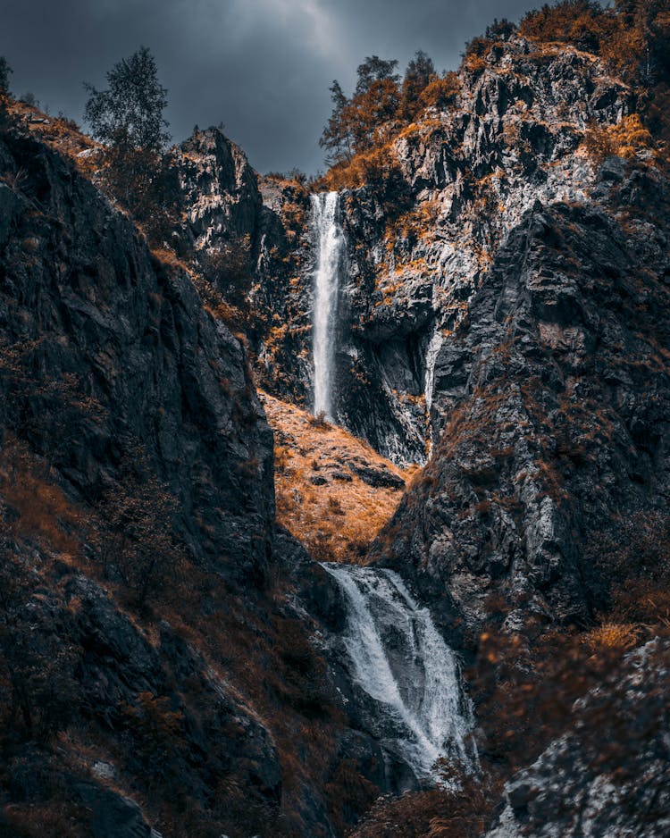 Waterfalls On Rocky Mountain Under Cloudy Sky