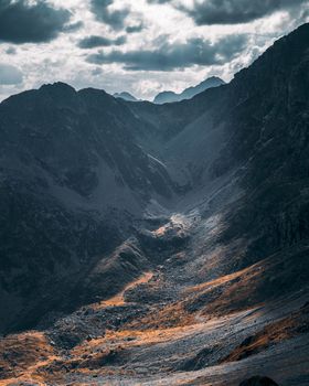 A breathtaking view of a rugged mountain valley under a dramatic cloudy sky, showcasing natural beauty.