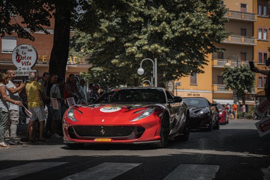 A vibrant street scene captures a red Ferrari amidst a bustling crowd during a city rally.
