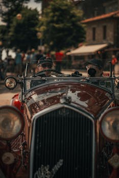 Two men driving a classic Alfa Romeo during a summer day.