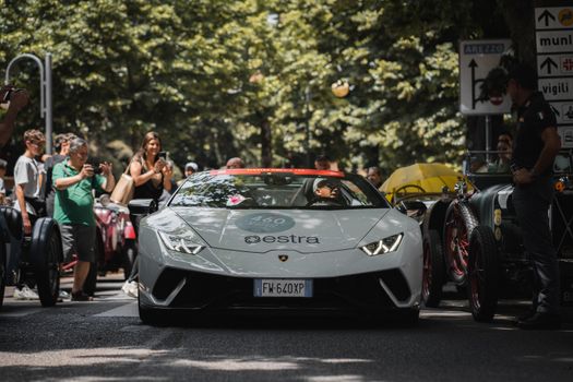 Dynamic street scene with a modern sports car and a captivated crowd during a racing event.