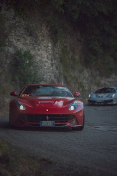 Vibrant red Ferrari sports car navigating a scenic mountain road with graceful curves.