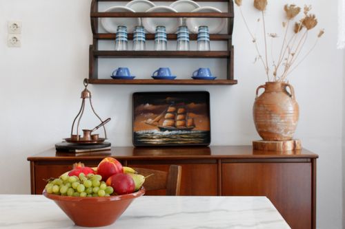Free Inviting rustic kitchen interior featuring a bowl of fresh fruits, vintage decor, and wooden shelves. Stock Photo