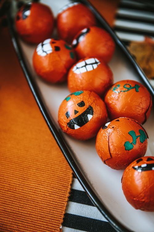 Free Close-up of Halloween-themed candy balls wrapped in colorful pumpkin foil on a tray. Stock Photo