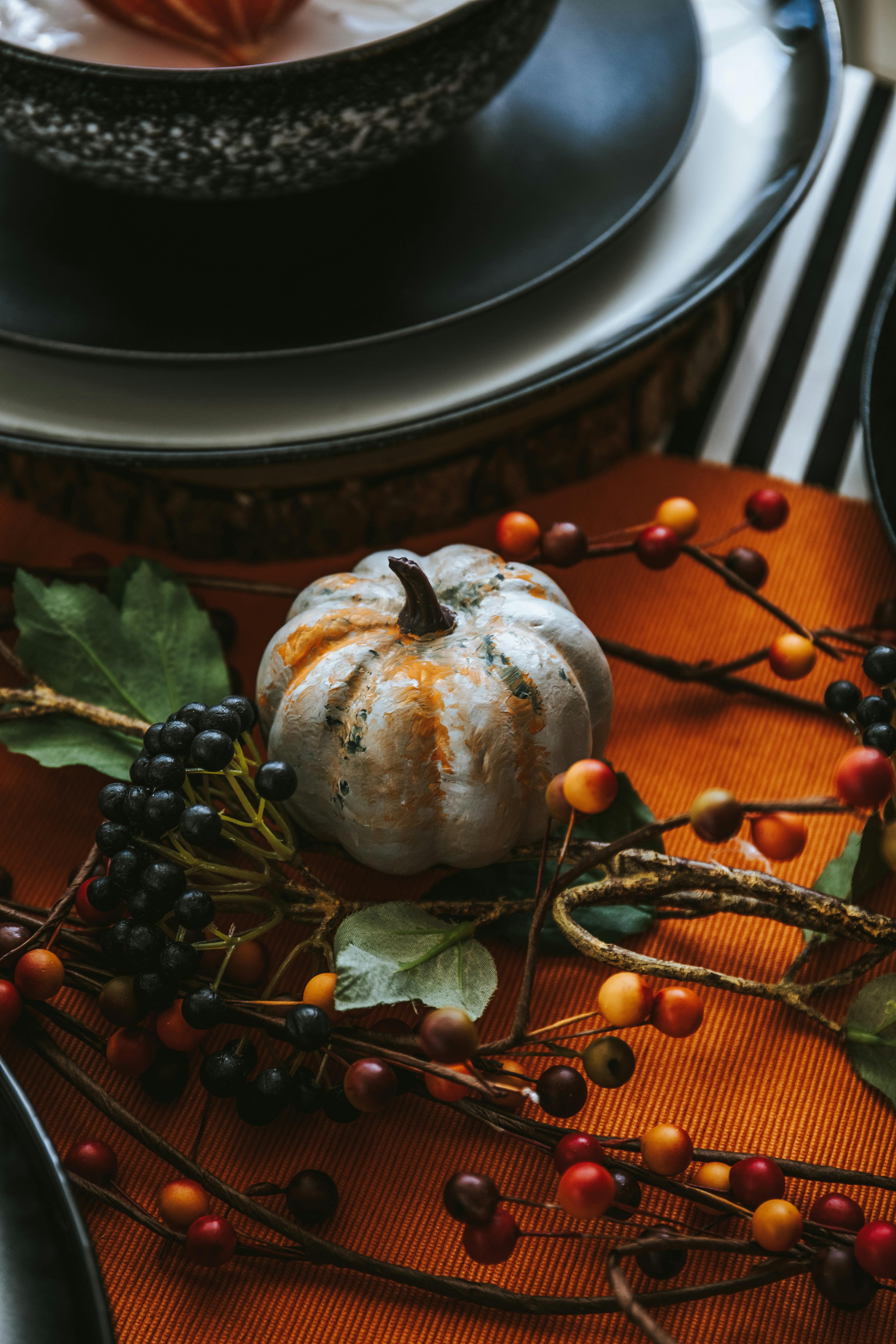 A decorative pumpkin centerpiece enhances this autumn-themed table setting.