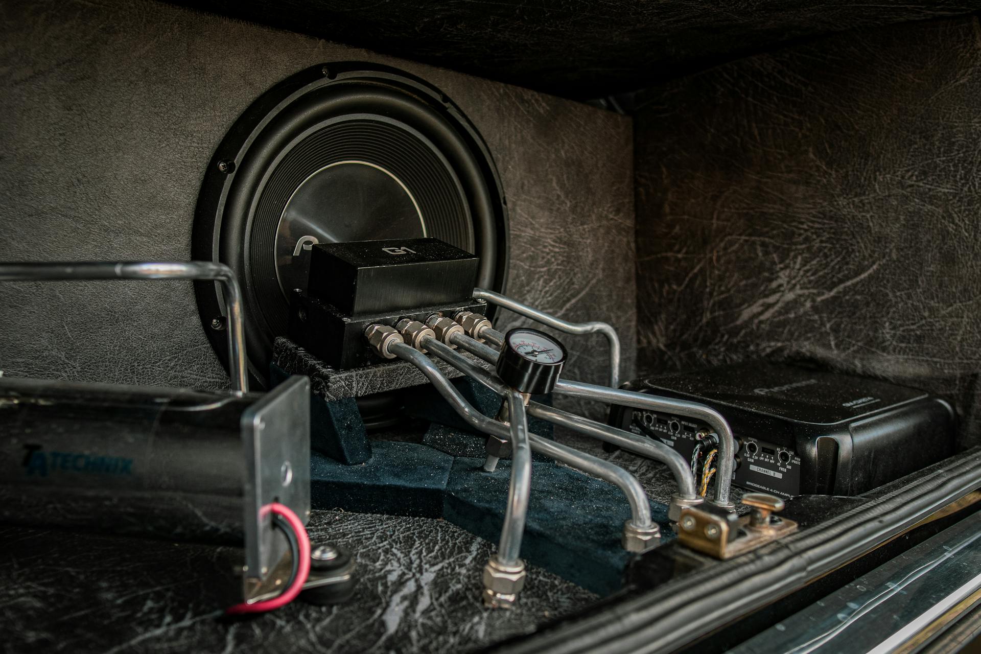 Close-up of an intricate car audio and hydraulic setup with metal components.