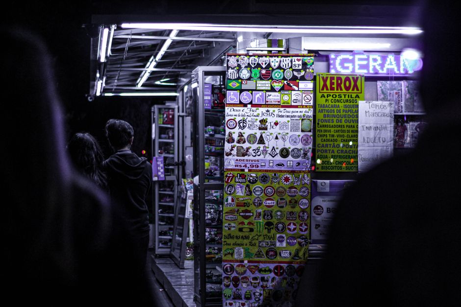 Nighttime view of a vibrant street souvenir shop adorned with colorful stickers and illuminated signs.
