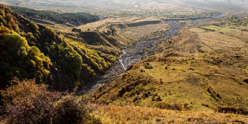 Free A breathtaking aerial view of a lush river valley surrounded by green hills under clear skies. Stock Photo