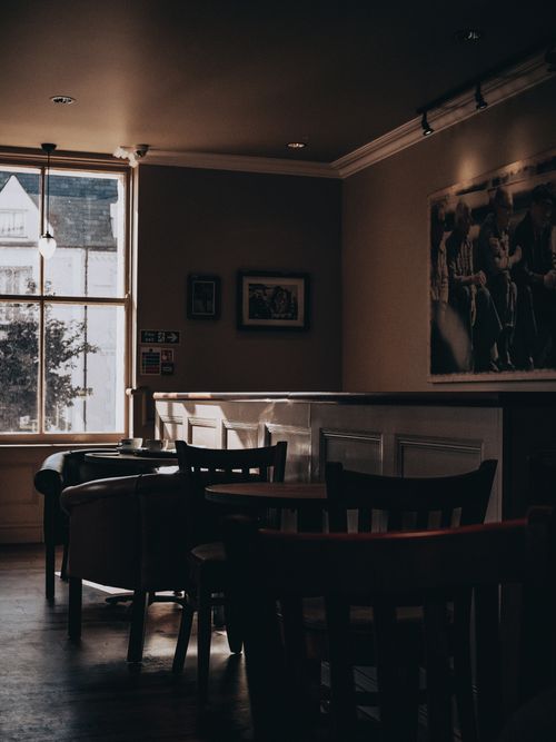 Free Warm and inviting café interior featuring vintage armchairs, wooden furniture, and soft lighting. Stock Photo