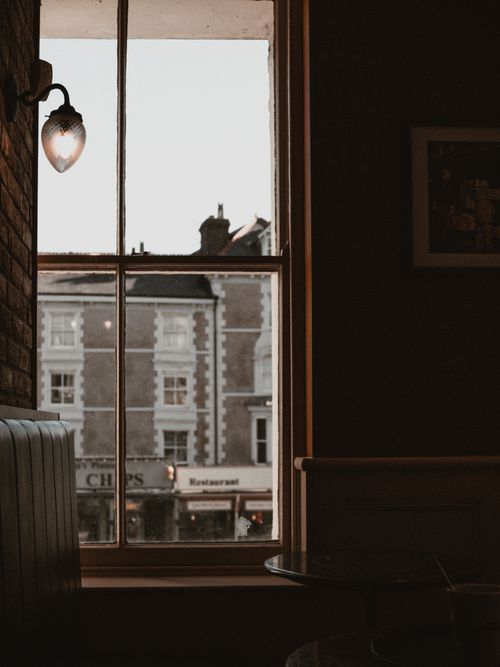 Free Warm, inviting café interior with window view of town buildings. Stock Photo