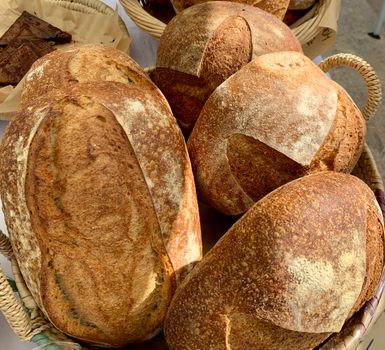 A selection of freshly baked artisan bread loaves displayed in wicker baskets.