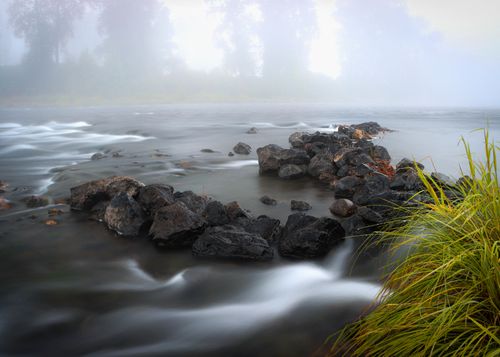 Free Peaceful river scene with flowing water and rocks on a foggy day. Stock Photo