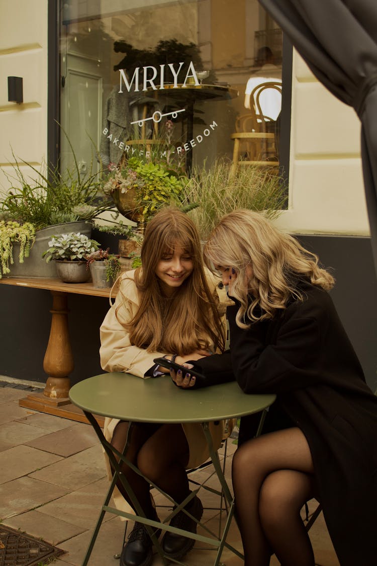 Friends Sitting At Sidewalk Cafe Table