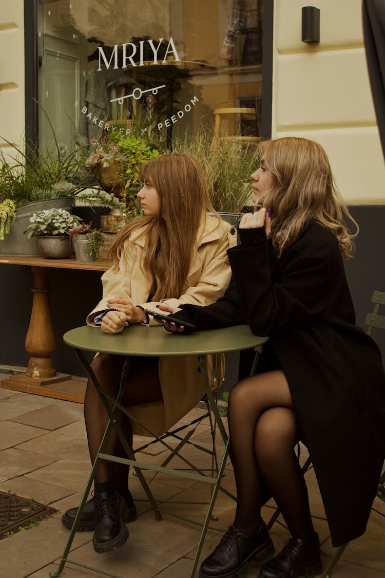 Girls Sitting At Outdoor Cafe Table