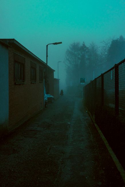 A mysterious alley cloaked in fog at dusk, creating a captivating and moody atmosphere.