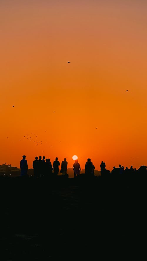 Silhouettes of People on Horizon on Sunset
