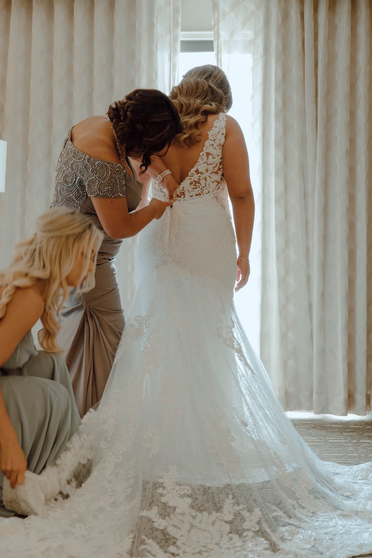 Women Helping In Wearing Wedding Dress