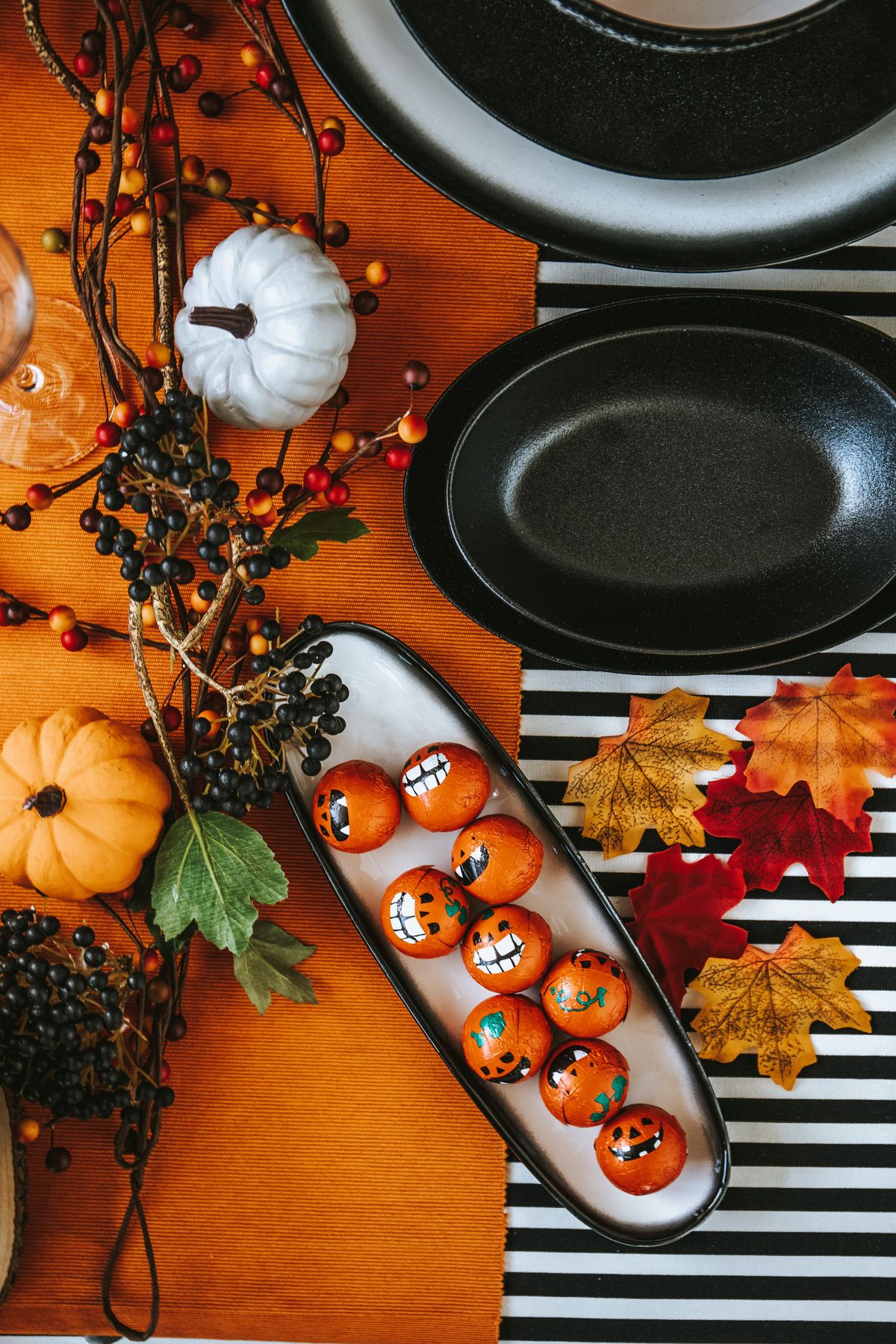 Festive Halloween table with painted pumpkins, berries, and autumn leaves