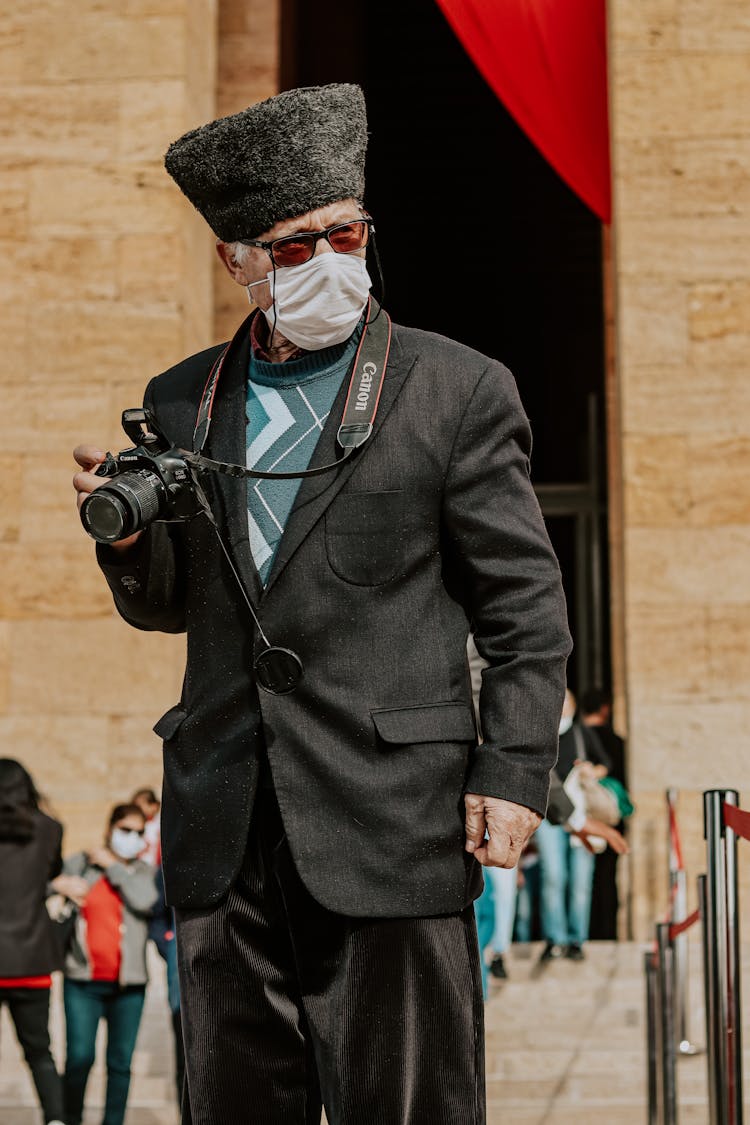 Elderly Man In A Medical Mask Holding A Canon Camera