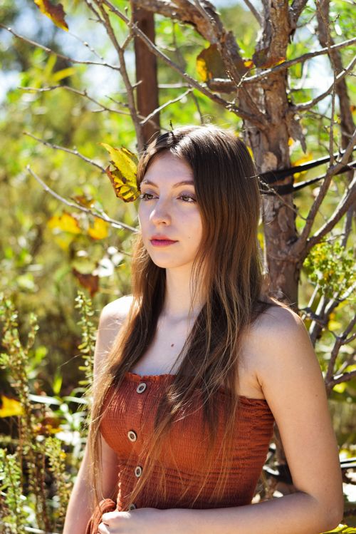 Free Young woman in brown dress outdoors enjoying the autumn sun. Stock Photo